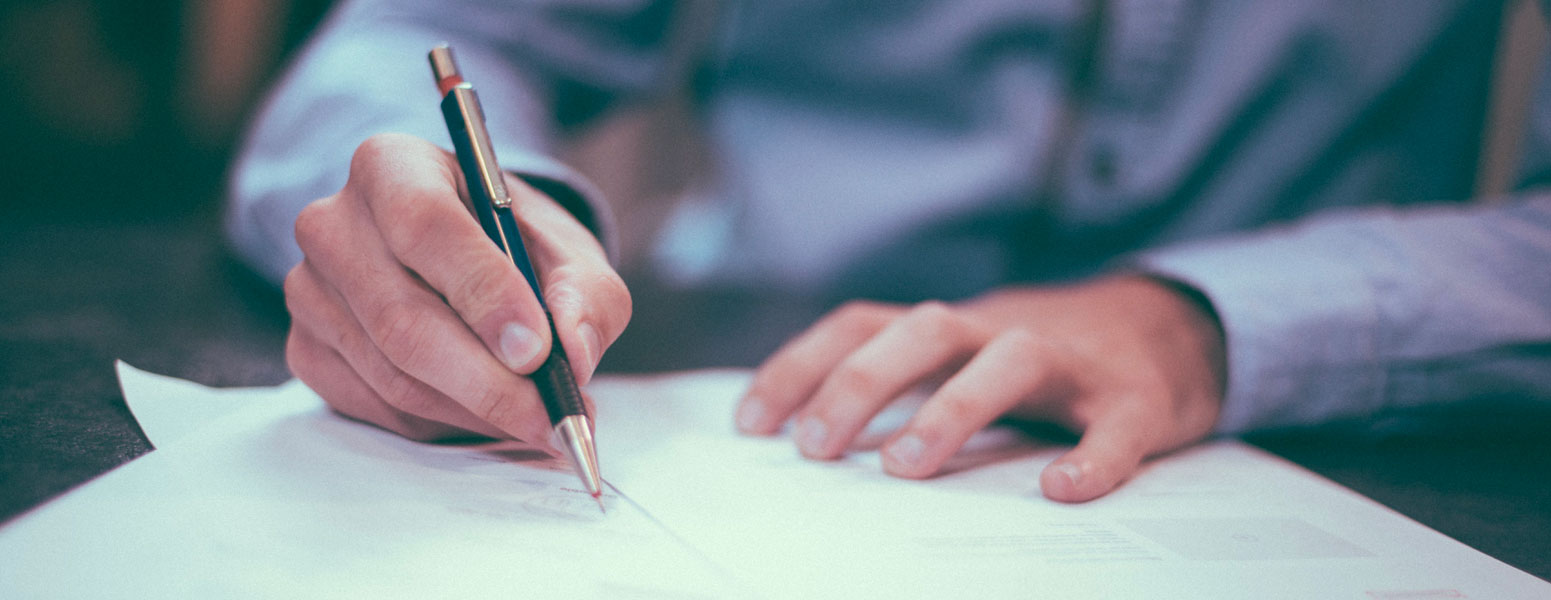 Man signing a legal document with black and gold pen