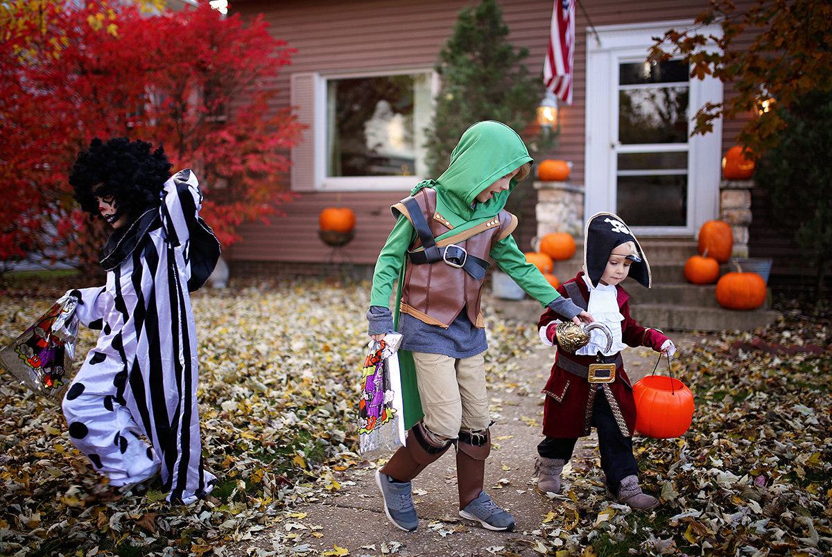 Two trick-or-treaters dressed as a ninja and a pirate practicing Halloween safety tips.