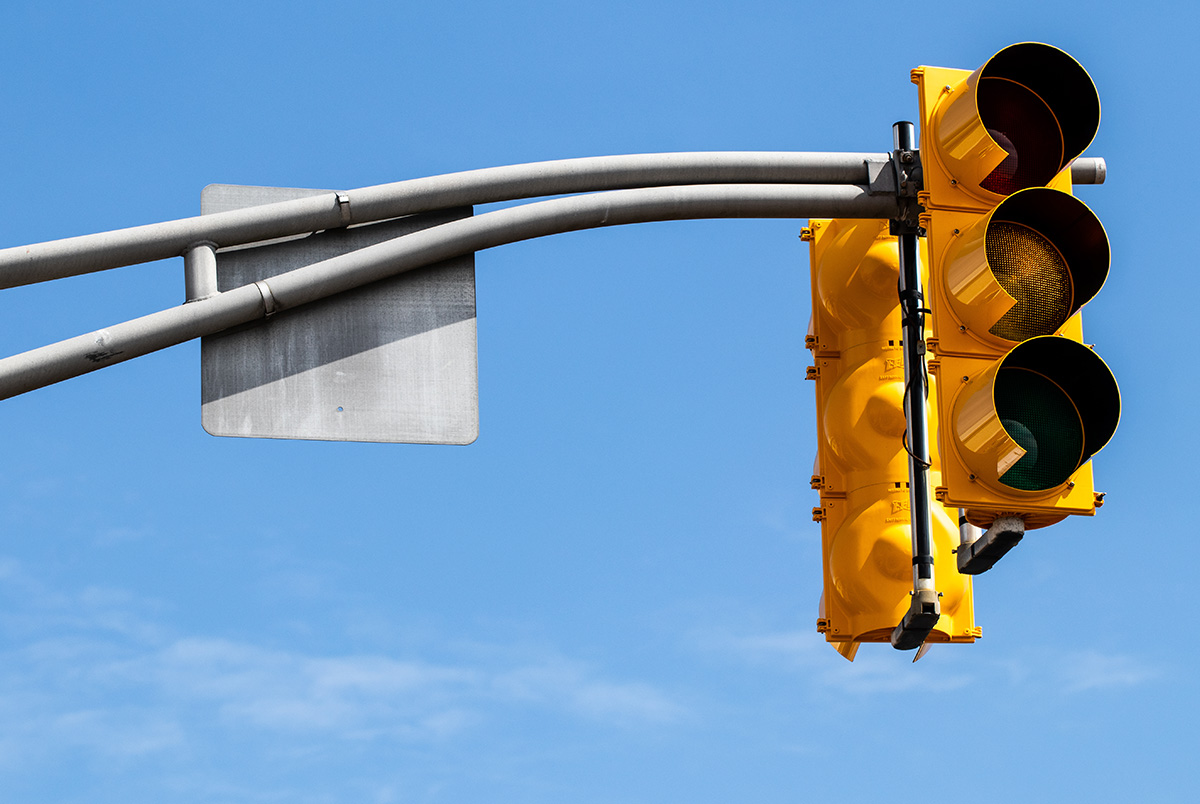A broken traffic signal with no lights.
