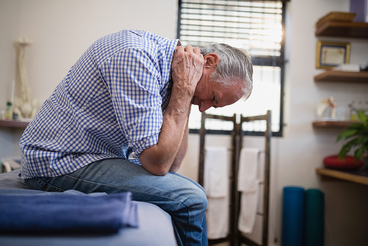 A man bent over holding is neck as an example of delayed injuries after an accident.