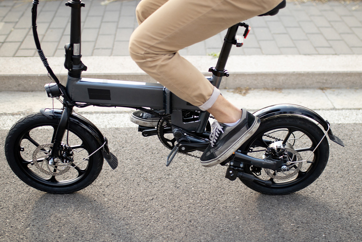 A close up of an e-bike on the road with a woman's legs in khaki pants to demonstrate e-bike safety.